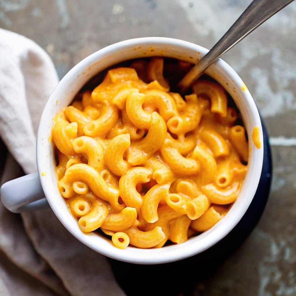Mac and cheese in a mug served hot on a kitchen counter